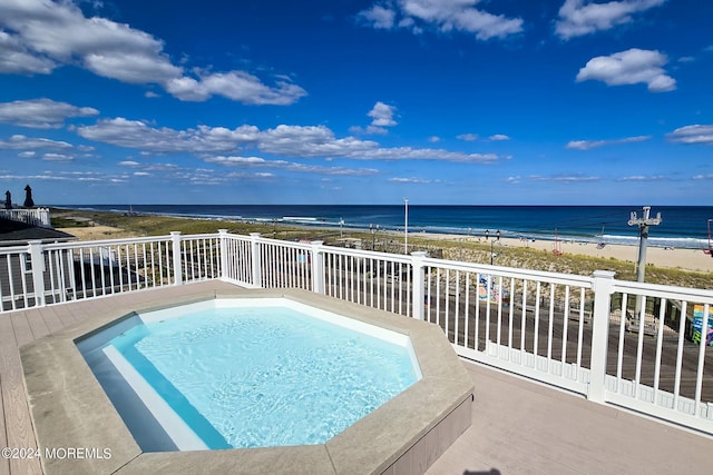 view of swimming pool featuring a view of the beach and a water view