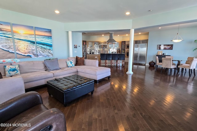 living area with recessed lighting, dark wood-type flooring, and decorative columns