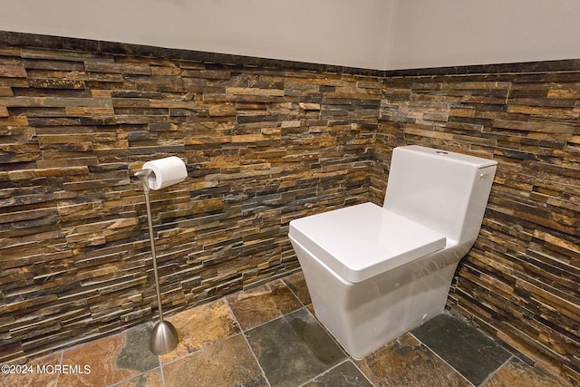 bathroom with stone tile flooring and tile walls