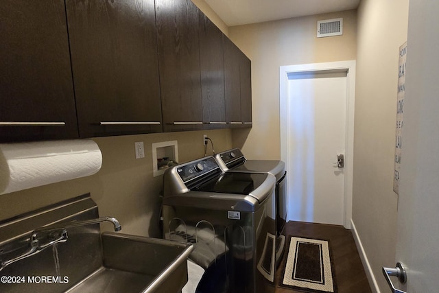 clothes washing area featuring visible vents, cabinet space, a sink, dark wood-type flooring, and washing machine and dryer