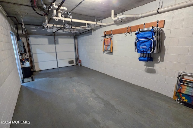 garage featuring concrete block wall, electric panel, and a garage door opener