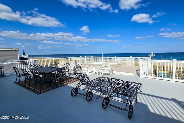 view of patio / terrace featuring a beach view, outdoor dining area, and a water view