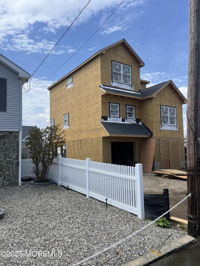 view of side of home with fence and roof with shingles