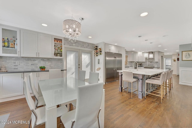 dining area featuring an inviting chandelier, sink, and light wood-type flooring