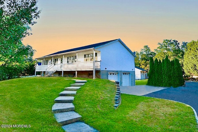 view of front of house featuring a garage, a porch, and a yard