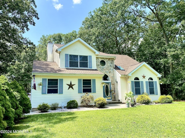 traditional-style home featuring roof with shingles, a chimney, and a front lawn