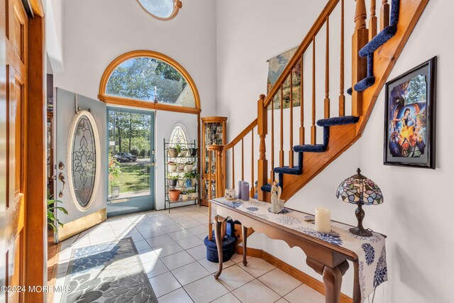 entryway featuring stairway, a high ceiling, and light tile patterned floors