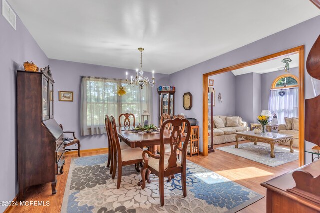 dining area featuring light wood finished floors, visible vents, and a notable chandelier