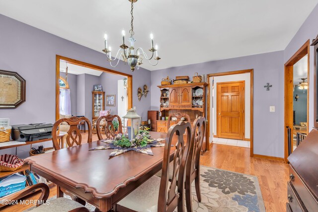 dining room with baseboards, an inviting chandelier, and light wood-style floors