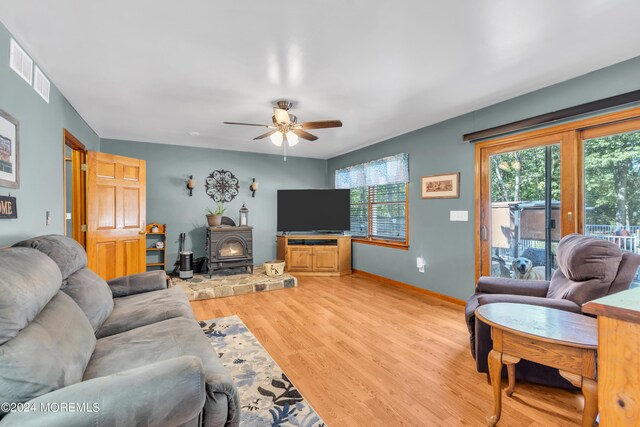 living area with a wealth of natural light, a wood stove, baseboards, and light wood finished floors