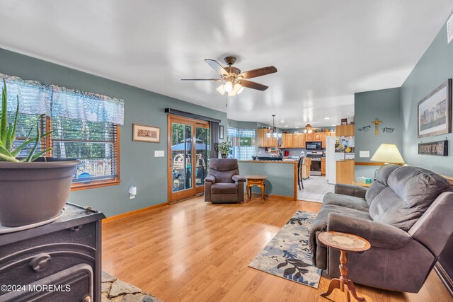 living area featuring ceiling fan, light wood-type flooring, and baseboards