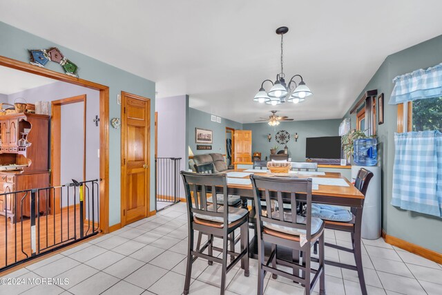 dining space featuring ceiling fan with notable chandelier, light tile patterned flooring, and baseboards