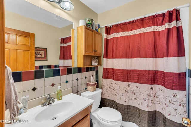 full bathroom with toilet, curtained shower, tile walls, and vanity