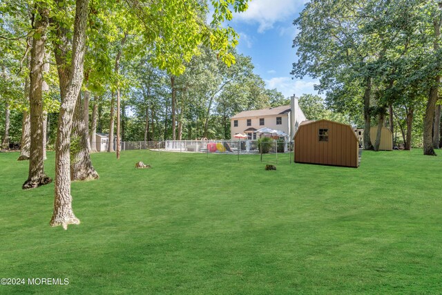 view of yard featuring a shed, an outdoor structure, and fence