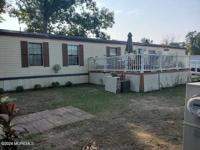 rear view of house with a lawn and a wooden deck