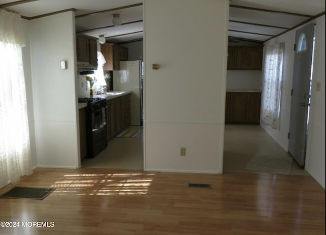 interior space with light wood-type flooring, stainless steel refrigerator, lofted ceiling, electric stove, and dark brown cabinets