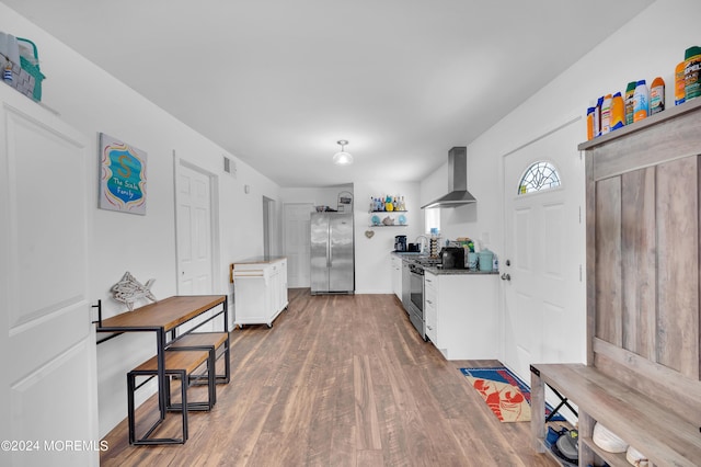 kitchen with visible vents, freestanding refrigerator, white cabinetry, wood finished floors, and wall chimney exhaust hood