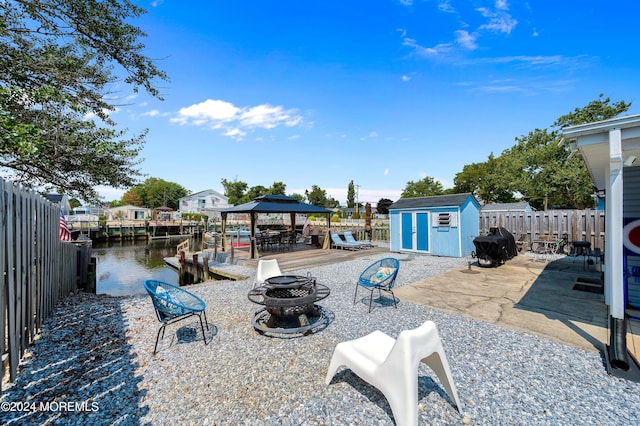 view of patio with a shed, a fire pit, a fenced backyard, and an outdoor structure