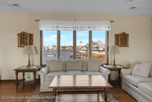 living room with dark hardwood / wood-style flooring and a water view