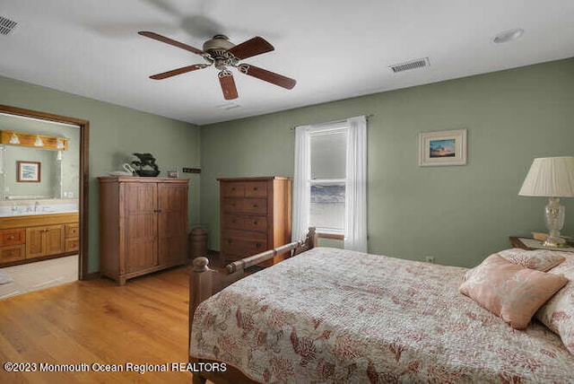 bedroom featuring ceiling fan, hardwood / wood-style floors, sink, and ensuite bathroom