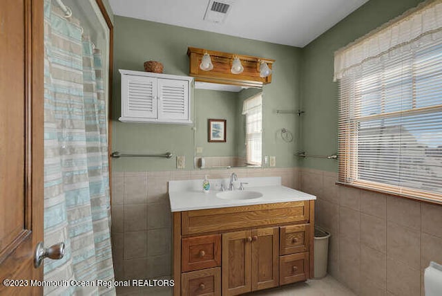 bathroom with tile walls, a shower with shower curtain, and vanity