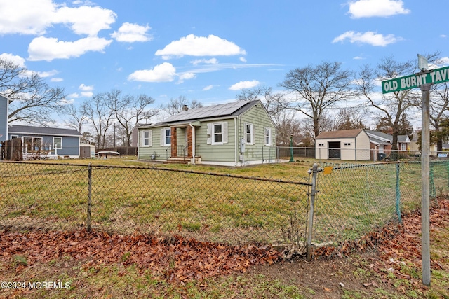 view of front of property featuring solar panels, a chimney, entry steps, a front lawn, and a fenced front yard