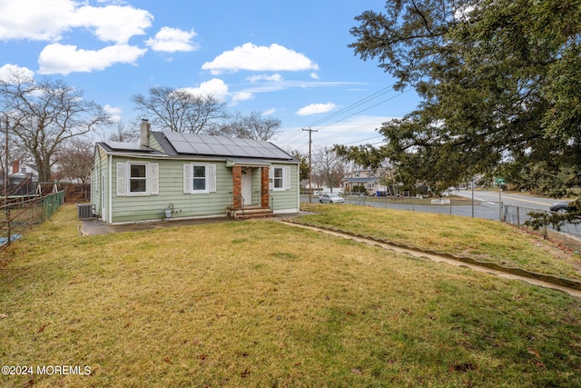 bungalow-style house featuring solar panels, a front lawn, and cooling unit