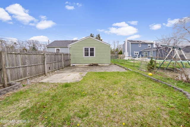 rear view of house featuring a patio, a yard, and a fenced backyard