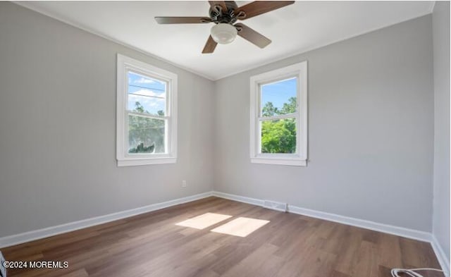 spare room featuring a ceiling fan, plenty of natural light, wood finished floors, and baseboards