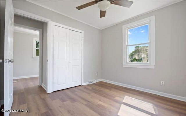 unfurnished bedroom with multiple windows, baseboards, and wood finished floors