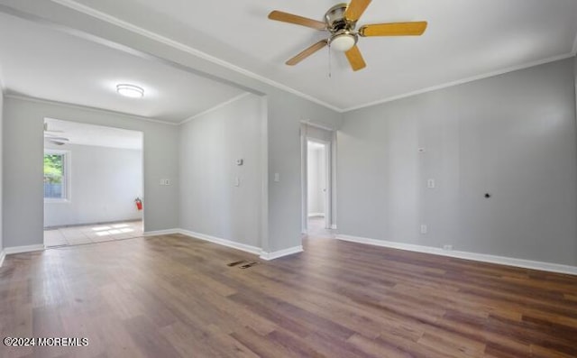 spare room featuring a ceiling fan, crown molding, wood finished floors, and baseboards