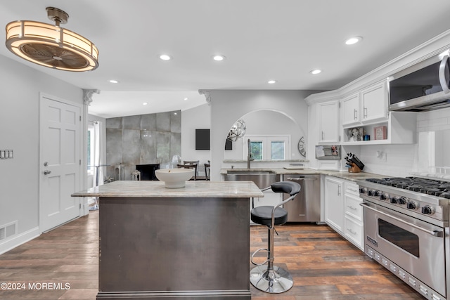 kitchen featuring appliances with stainless steel finishes, a kitchen bar, dark hardwood / wood-style floors, and vaulted ceiling