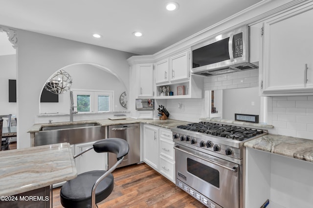 kitchen featuring white cabinetry, tasteful backsplash, stainless steel appliances, dark hardwood / wood-style flooring, and light stone countertops