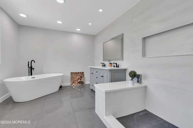 bathroom with a tub to relax in, vanity, and tile patterned flooring