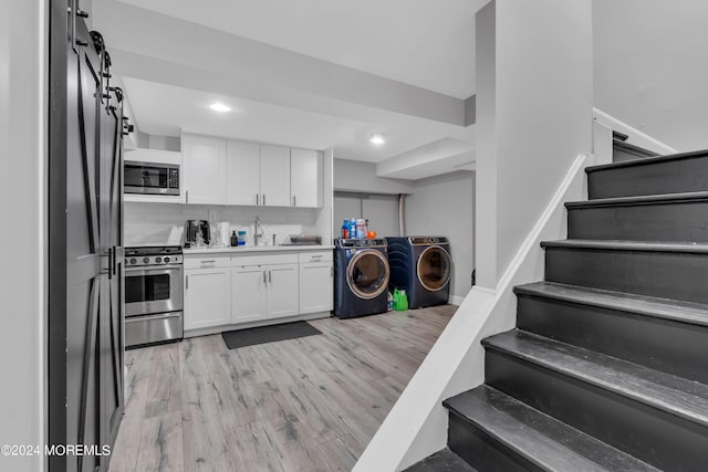 kitchen with light hardwood / wood-style flooring, stainless steel appliances, washer and clothes dryer, and decorative backsplash