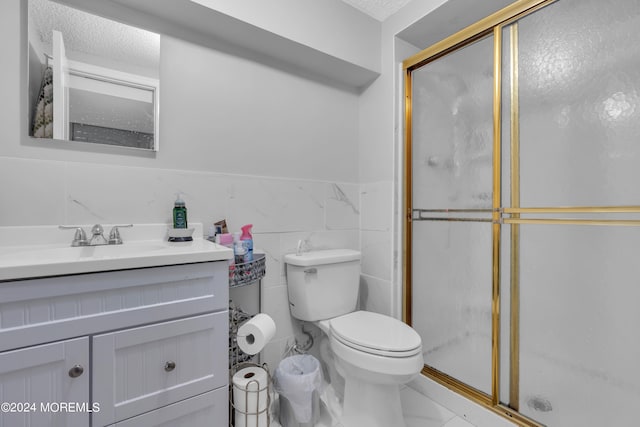 bathroom with toilet, tile patterned floors, a shower with door, vanity, and tile walls