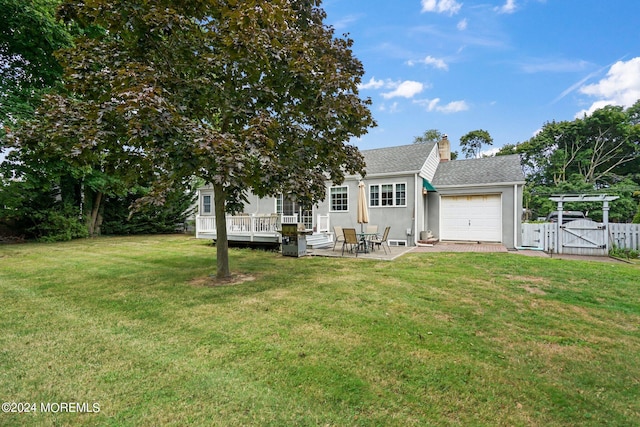 rear view of property featuring a patio area, a deck, a lawn, and a garage