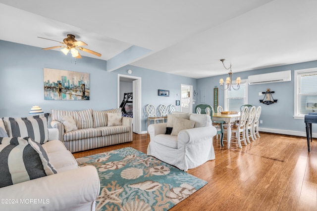 living room featuring ceiling fan with notable chandelier, hardwood / wood-style floors, a baseboard heating unit, and a wall unit AC