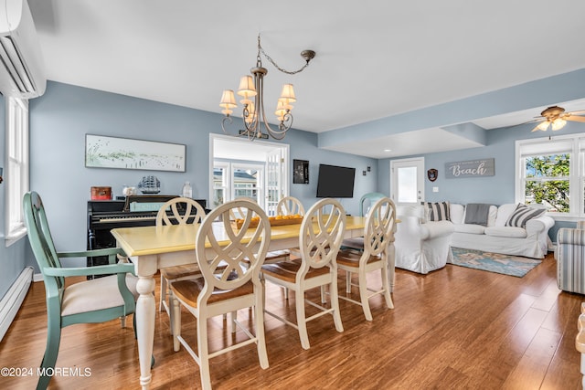 dining space featuring ceiling fan with notable chandelier, hardwood / wood-style floors, a wall unit AC, and a baseboard radiator