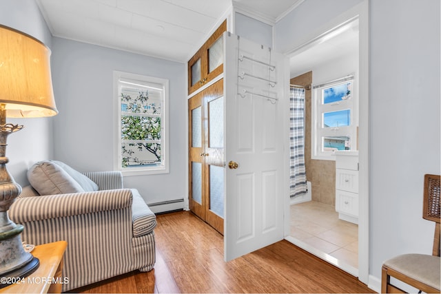 sitting room featuring a baseboard heating unit, hardwood / wood-style flooring, and crown molding