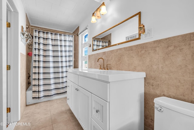 full bathroom with tile walls, tile patterned flooring, shower / tub combo with curtain, vanity, and toilet