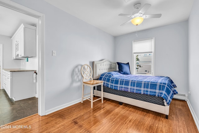 bedroom with ceiling fan, hardwood / wood-style flooring, and baseboard heating