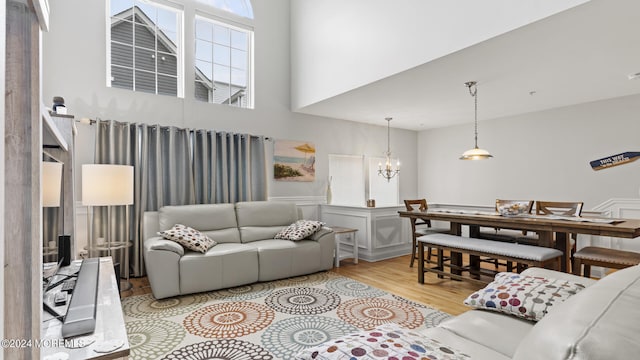 living room featuring light wood-type flooring, a notable chandelier, and a high ceiling