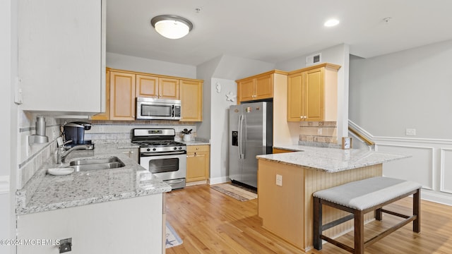 kitchen featuring light wood-type flooring, sink, decorative backsplash, appliances with stainless steel finishes, and light brown cabinets