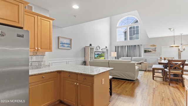 kitchen featuring stainless steel fridge, a wealth of natural light, kitchen peninsula, and light hardwood / wood-style flooring