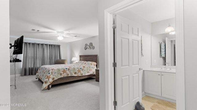 bedroom featuring light colored carpet, ceiling fan, sink, and ensuite bathroom