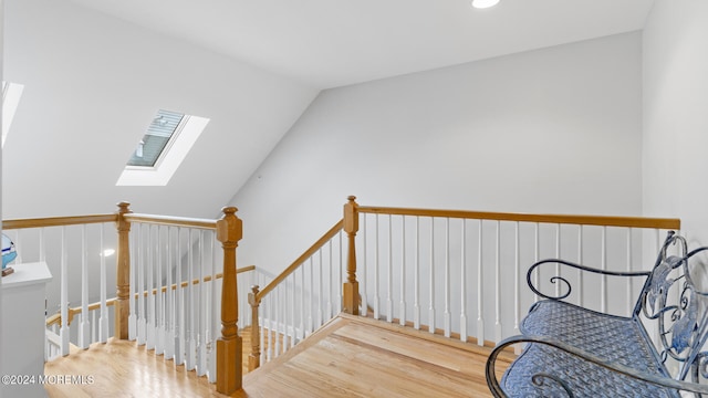 stairway featuring vaulted ceiling with skylight and wood-type flooring