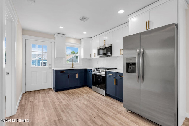 kitchen with light hardwood / wood-style flooring, stainless steel appliances, tasteful backsplash, and blue cabinetry