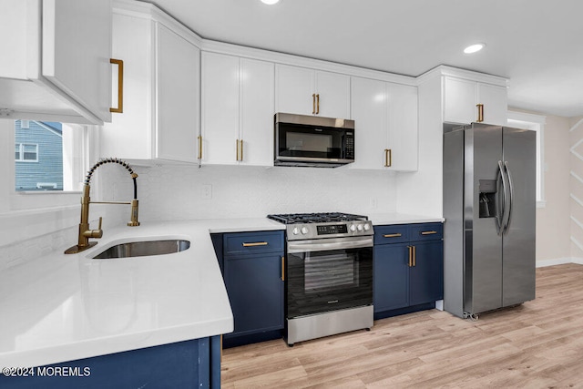 kitchen with light hardwood / wood-style flooring, blue cabinetry, appliances with stainless steel finishes, sink, and white cabinetry