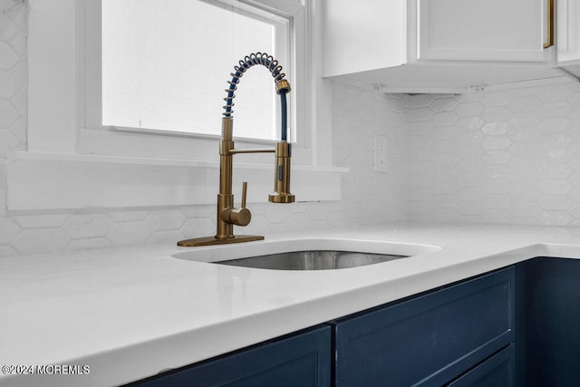 interior details with blue cabinets, sink, and tasteful backsplash